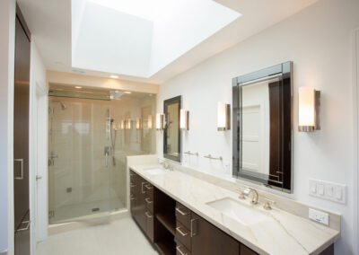 master bathroom with double sinks and walk in shower and skylight