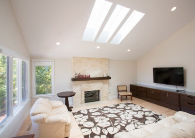living room with tile fireplace and vaulted ceiling with skylight
