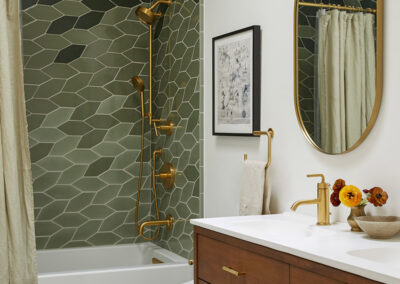 full bathroom with modern botanical tile in shades of green and mid century style vanity and brass fixtures