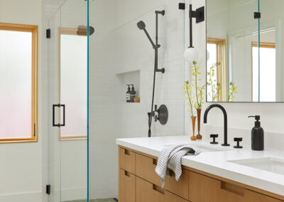 clean modern bathroom featuring geometric tile flooring and natural wood vanity with seamless glass shower